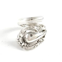 a silver ring with an intricate design on the front and side, set against a white background