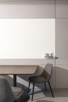 two chairs and a table in a room with a white board on the wall behind them