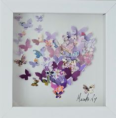 a white frame filled with lots of purple and pink butterfly cut outs on top of each other