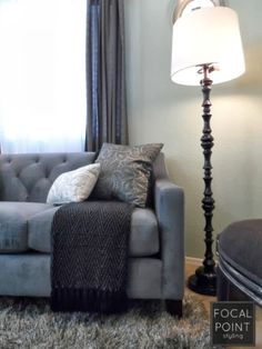 a gray couch sitting next to a lamp in a living room