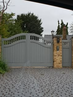 a brick driveway with a stone fence and gate