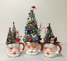 three santa claus mugs with christmas trees and ornaments on them, sitting next to each other