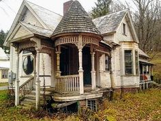 an old run down house sitting in the middle of a field with leaves on the ground