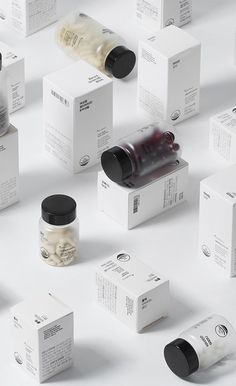 many different types of medicine bottles on a white surface with black caps and labels around them