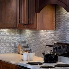 a stove top oven sitting inside of a kitchen next to wooden cupboards and white counter tops