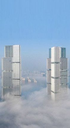 two skyscrapers in the sky above some clouds