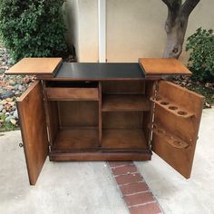 an old fashioned wooden cabinet with sliding doors on the front and side, sitting next to a tree