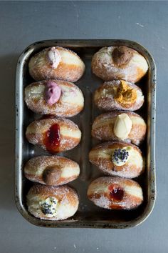 there are many donuts with different toppings in the tin on the table top