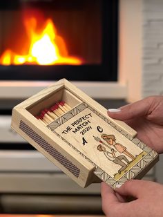 a person holding a match box with matches in front of a fire place