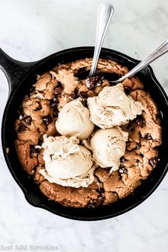 a skillet with ice cream and chocolate chip cookies in it on a marble surface