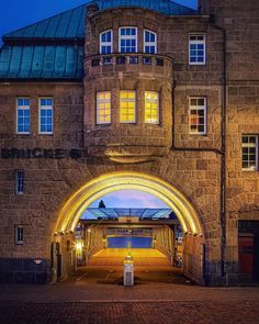 the entrance to an old brick building with a lit up archway at night time,