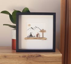 a wooden shelf with a framed artwork and potted plant