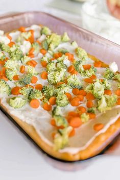 a casserole dish with carrots and broccoli on it