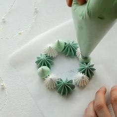 someone is decorating a wreath with green and white decorations