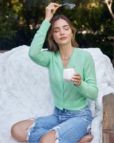 a woman sitting on a bench holding a cup