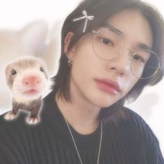 a man with glasses and a ferret on his shoulder is looking at the camera