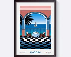 a framed poster with a table and chairs in front of an ocean view