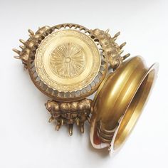 an ornately decorated gold ring dish sits on a white surface next to two rings