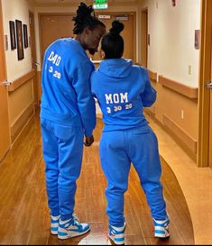 two people in matching blue tracksuits are facing each other while standing on a wooden floor