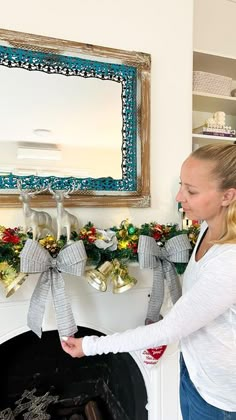 a woman standing in front of a fireplace decorated for christmas