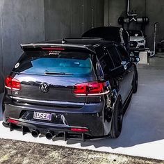 the back end of a car parked in a garage with its trunk open and it's hood up