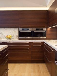 a modern kitchen with wood cabinets and marble counter tops, along with wooden flooring