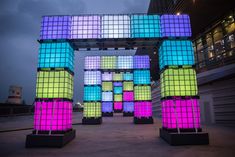 colorful cubes are stacked on top of each other in front of a large building