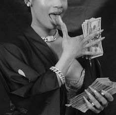 a black and white photo of a woman with money in her hand, making a funny face