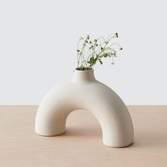 a white vase with flowers in it sitting on a table