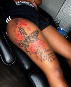 a woman sitting on top of a black chair next to a table with a tattoo on her leg