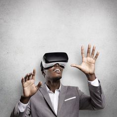 a man in a suit wearing a virtual reality headset and holding his hands up