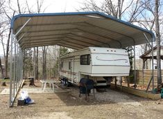 an rv is parked under a carport in the woods