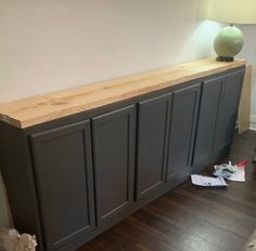 a large wooden cabinet sitting on top of a hard wood floor next to a lamp