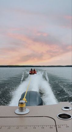 two people on a speedboat in the water at sunset or dawn with pink clouds