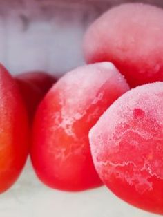 some red fruit are sitting in a white container with water droplets on the top and bottom