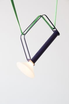 a black and green light hanging from a ceiling fixture with a white lamp on it