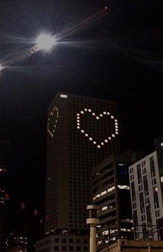 the city lights are lit up in the night sky and heart is written on the building