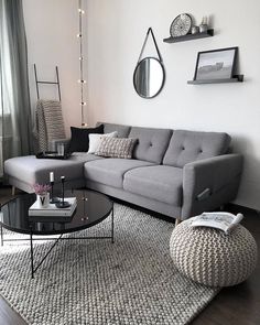 a living room with a gray couch and round coffee table in front of a window