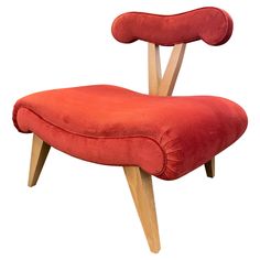 a red chair with wooden legs and a foot rest on it's back end