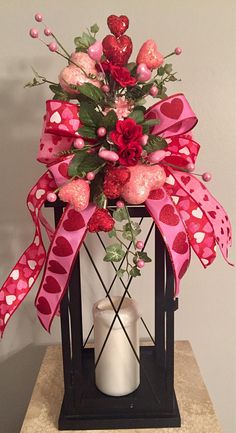 a valentine's day arrangement in a lantern with roses and hearts on the ribbon