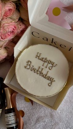 a cake in a box with the words happy birthday written on it next to some flowers