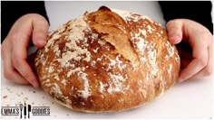 a person holding a loaf of bread on top of a white countertop with powdered sugar sprinkled on it