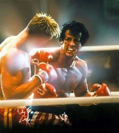 two men boxing in the ring with one wearing red and white shorts