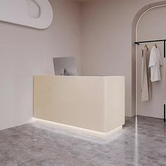 a white reception desk in an office with clothes on hangers