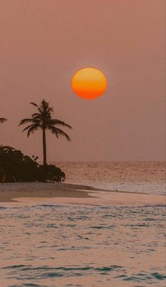 the sun is setting over an island with palm trees