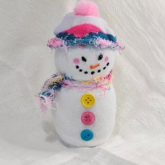 a stuffed snowman wearing a hat and scarf with buttons on it's chest