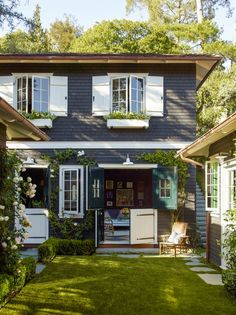 a house with white shutters on the windows and green grass in front of it