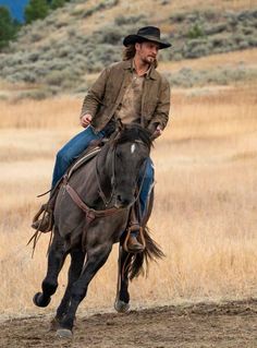 a man riding on the back of a brown horse in a dry grass covered field