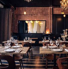 an empty restaurant with wooden tables and chairs, chandeliers hanging from the ceiling