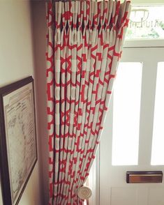 red and white curtains hanging on the side of a door in front of a window